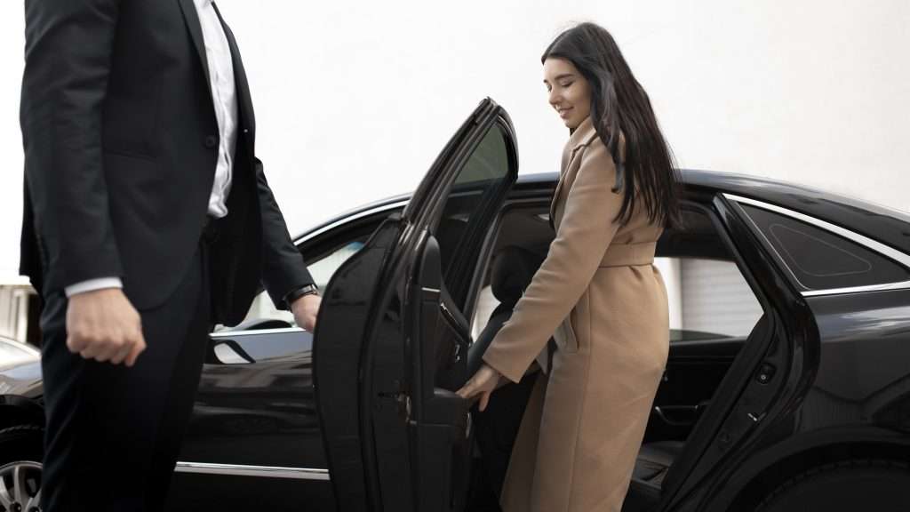 A woman enters a car with the driver holding the door open for her, Lauryn Hill Tour.