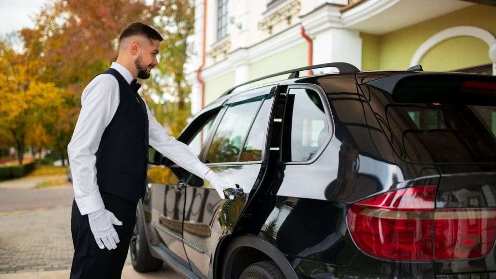 Chauffeur opening car door for luxury passengers