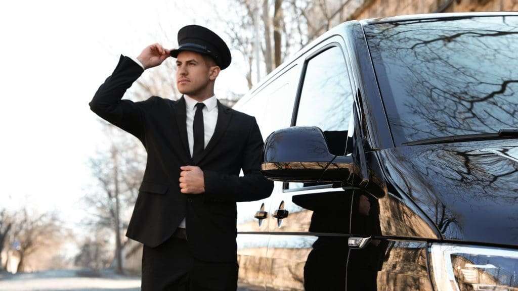 Discreet and Confidential chauffeur beside black vehicle
